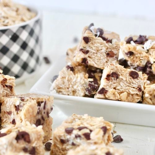 Copycat Oatmeal Cookie Heavenly Hunks Recipe 5 | Milk & Honey Nutrition Homemade Heavenly Hunks oatmeal chocolate chip squares piled on plates beside a bowl of rolled oats.