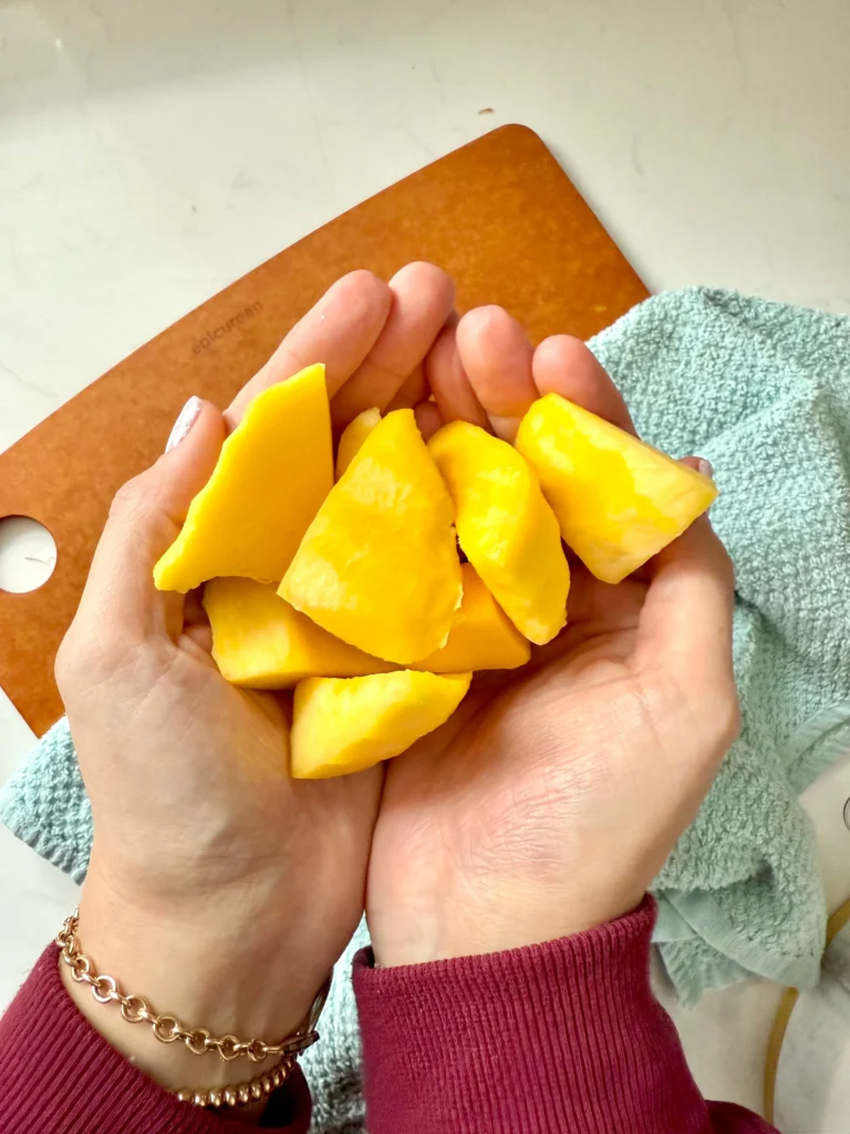 hands holding 1 cup mango cubes